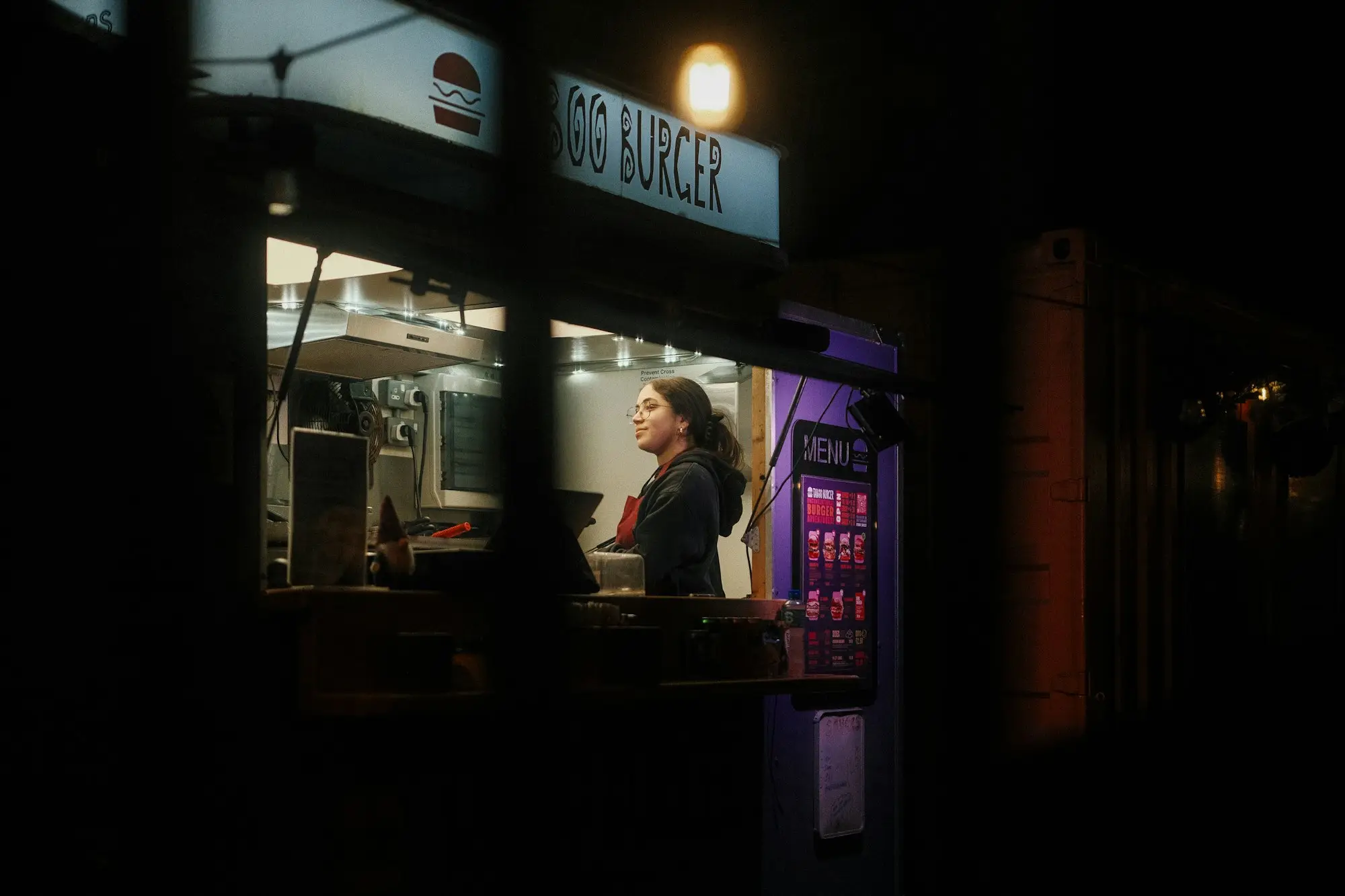 Franchisee standing behind the counter of a busy takeaway outlet, considering a cash flow loan for the store
