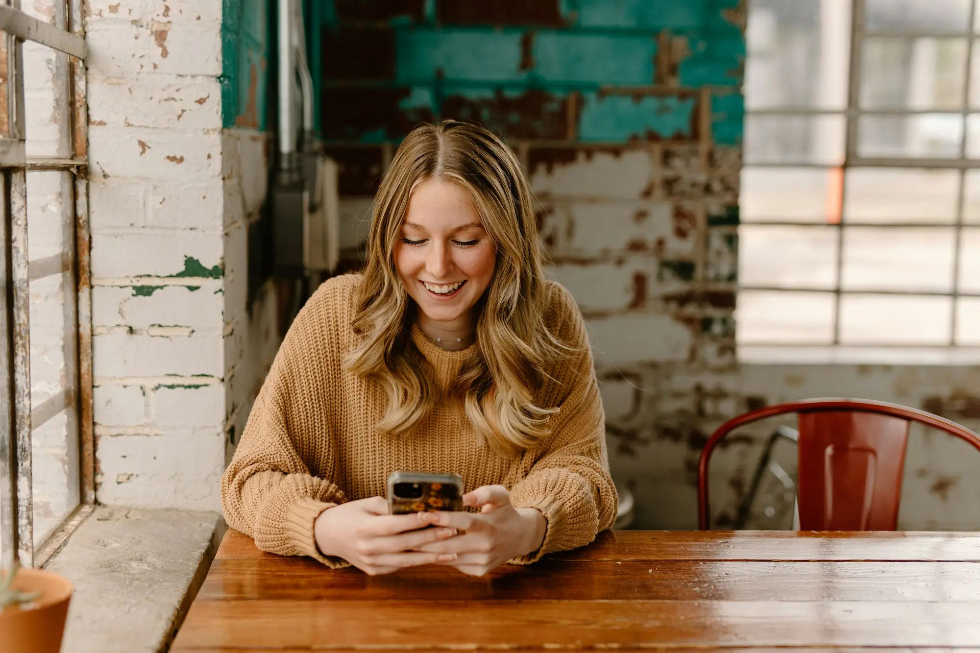 Café owner checking a banking app on her phone at the counter to plan daily or weekly business loan repayments