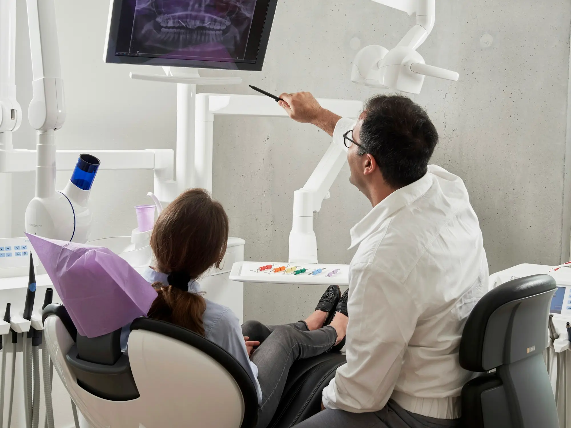 Dentist reviewing a 3D cone beam CT scan on a monitor, illustrating CBCT scanner finance for a dental practice
