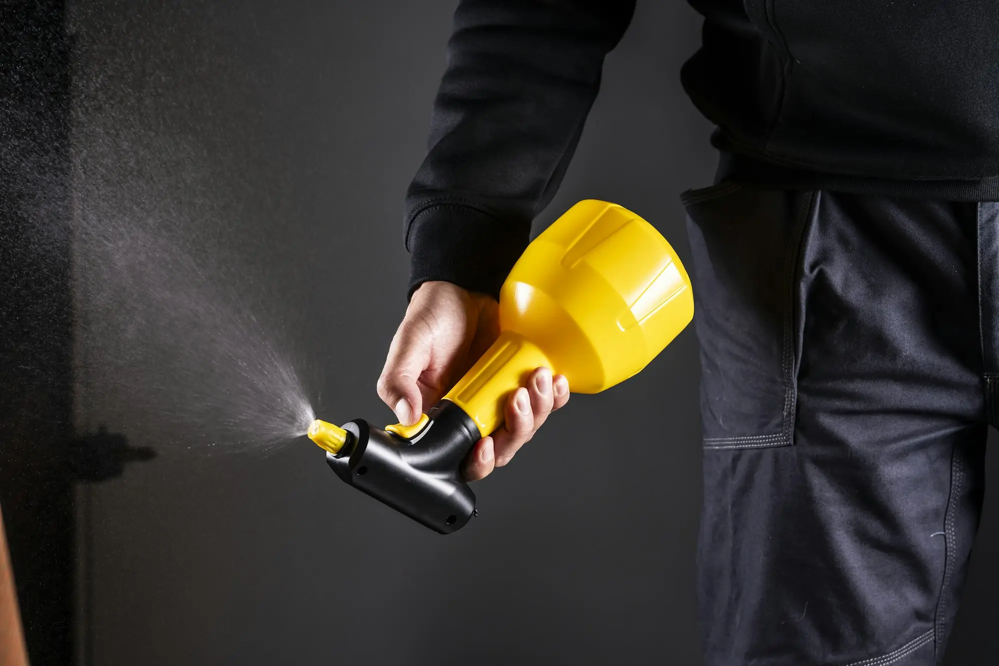 Pest control technician in protective gear treating the outside of a house