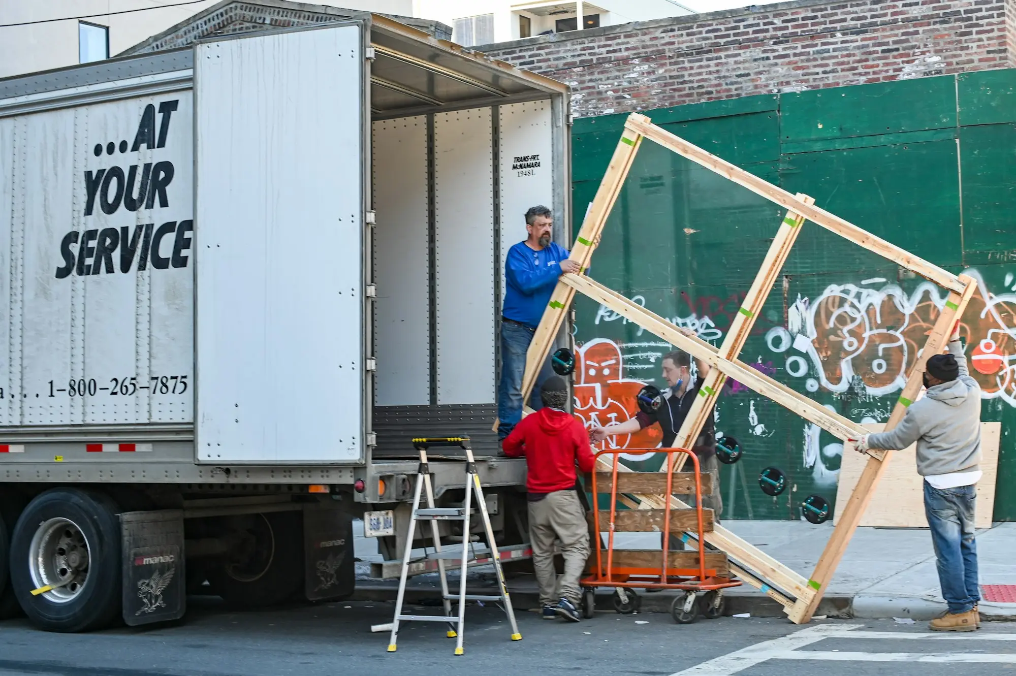 Removalists loading wrapped furniture into a moving truck outside a home