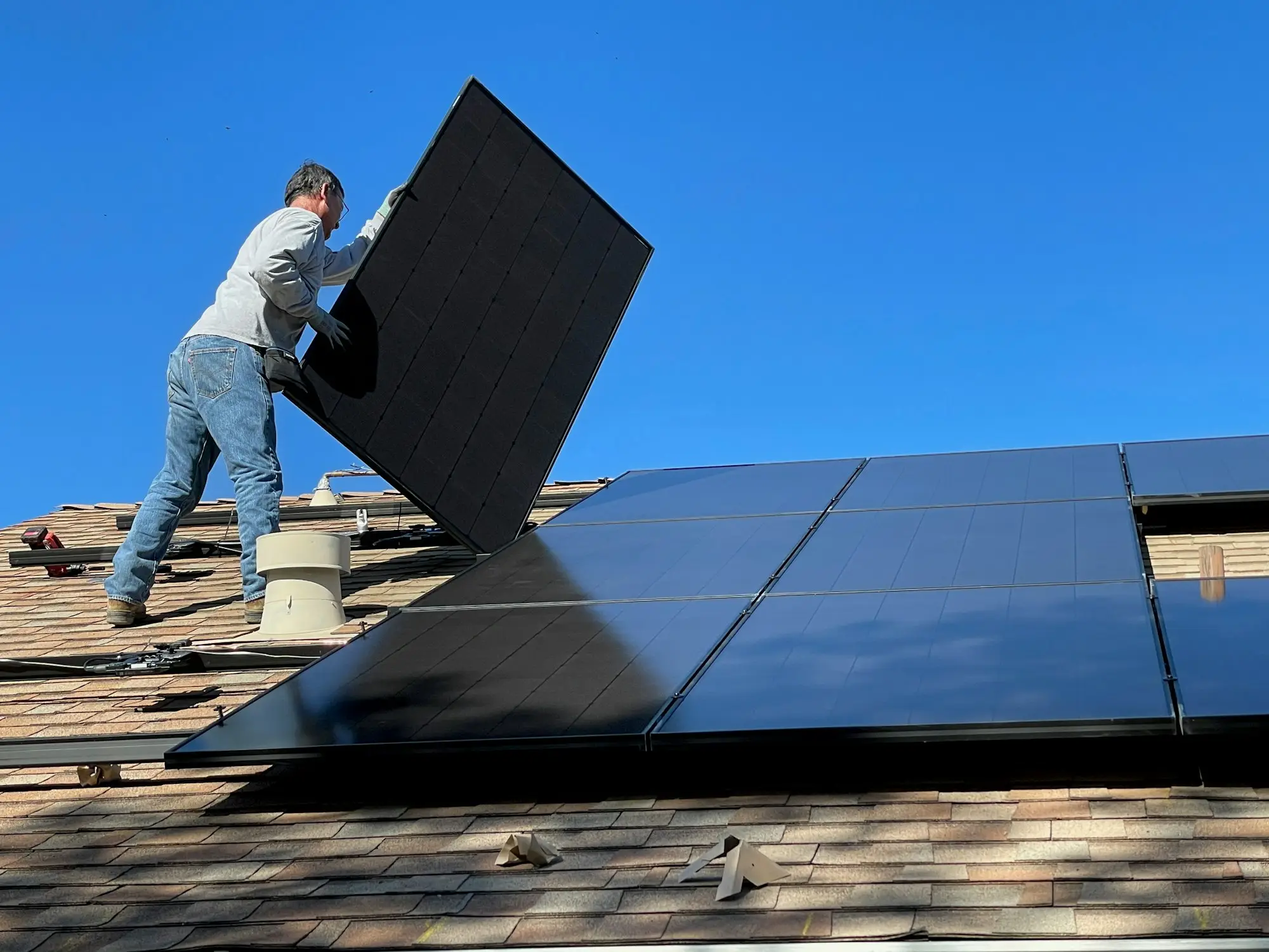 Solar installer fitting panels to a residential roof on a sunny day