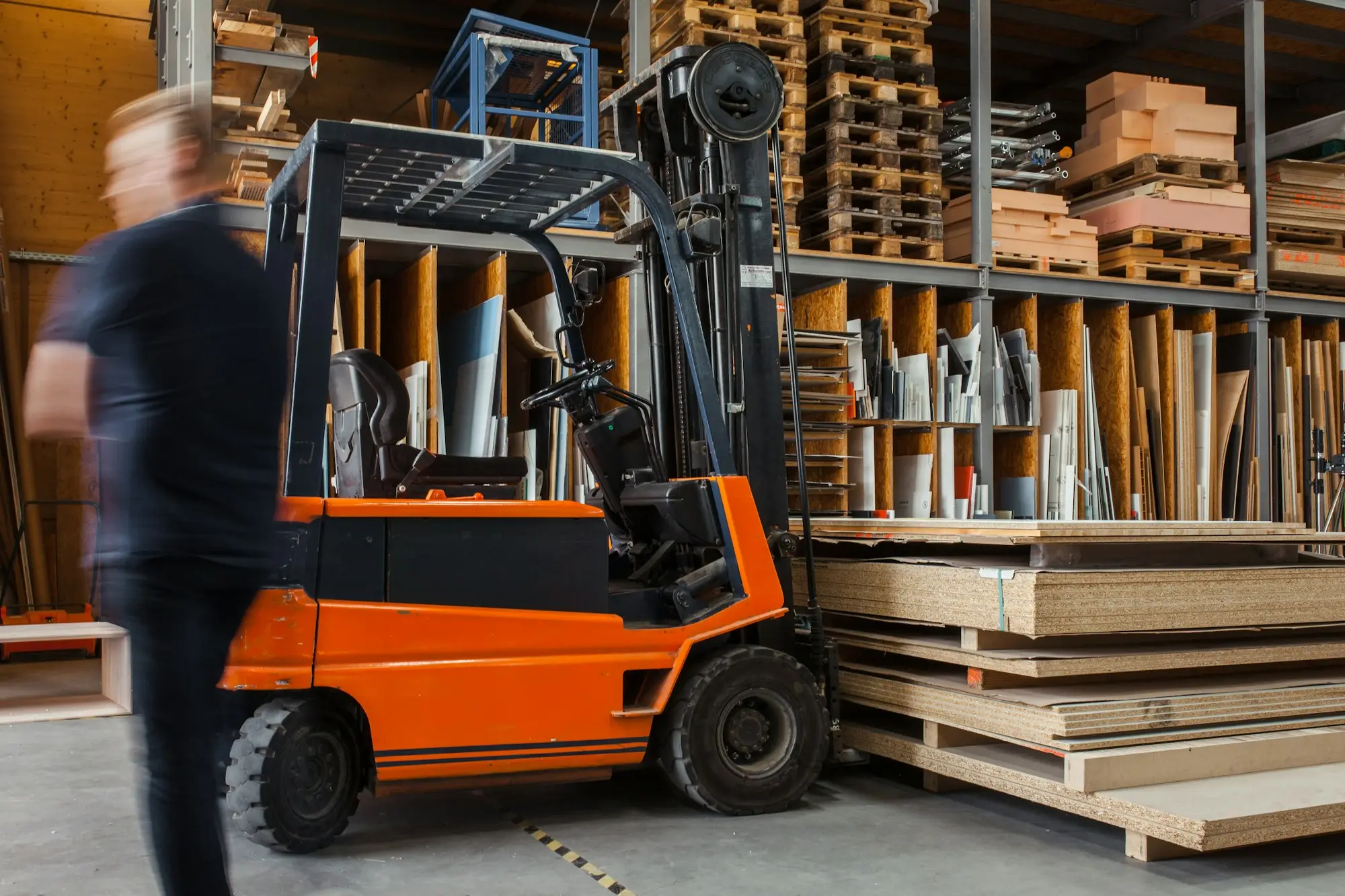 Forklift moving pallets of stock in a wholesale distribution warehouse