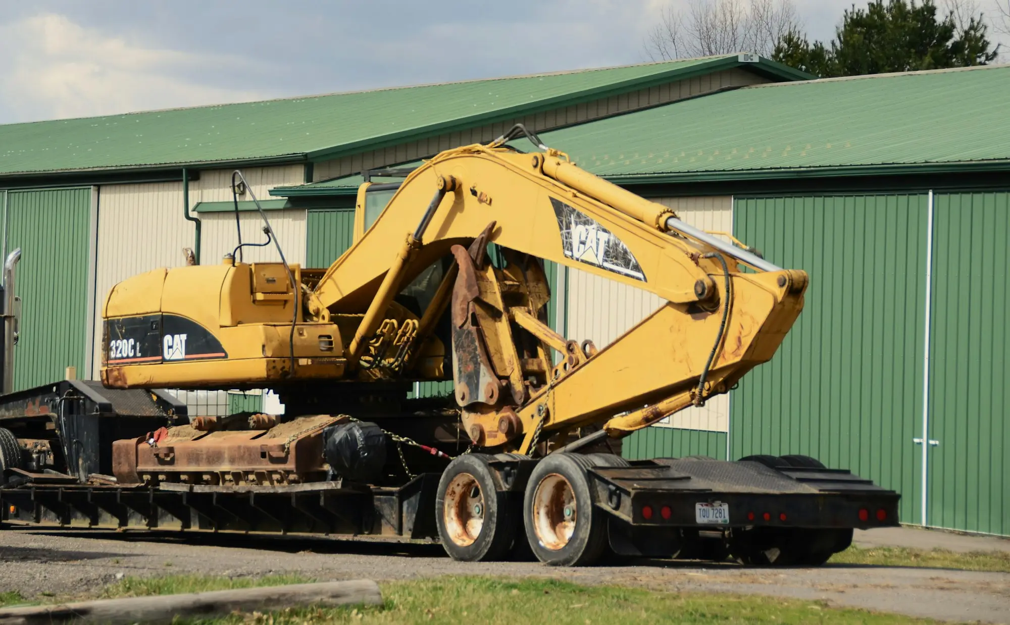 Excavator chained down on a float trailer between sites, a common moment where insurance on financed machinery matters