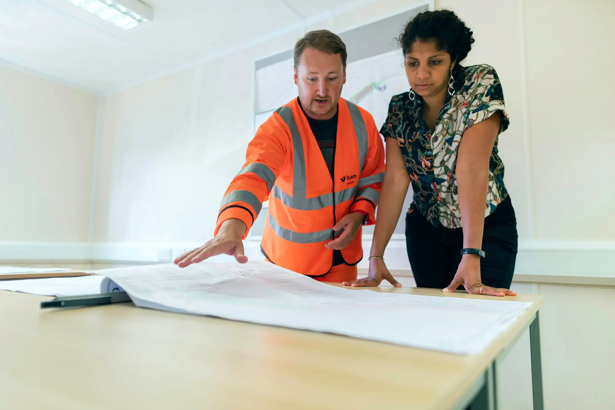 Small developer reviewing a fixed-price building contract and townhouse plans at a table before applying for a construction loan