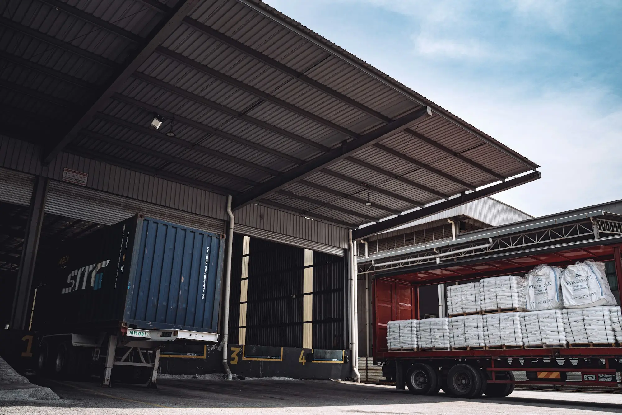 Pallets being loaded onto a right-hand-drive delivery truck at a wholesaler's loading dock as freight surcharges rise