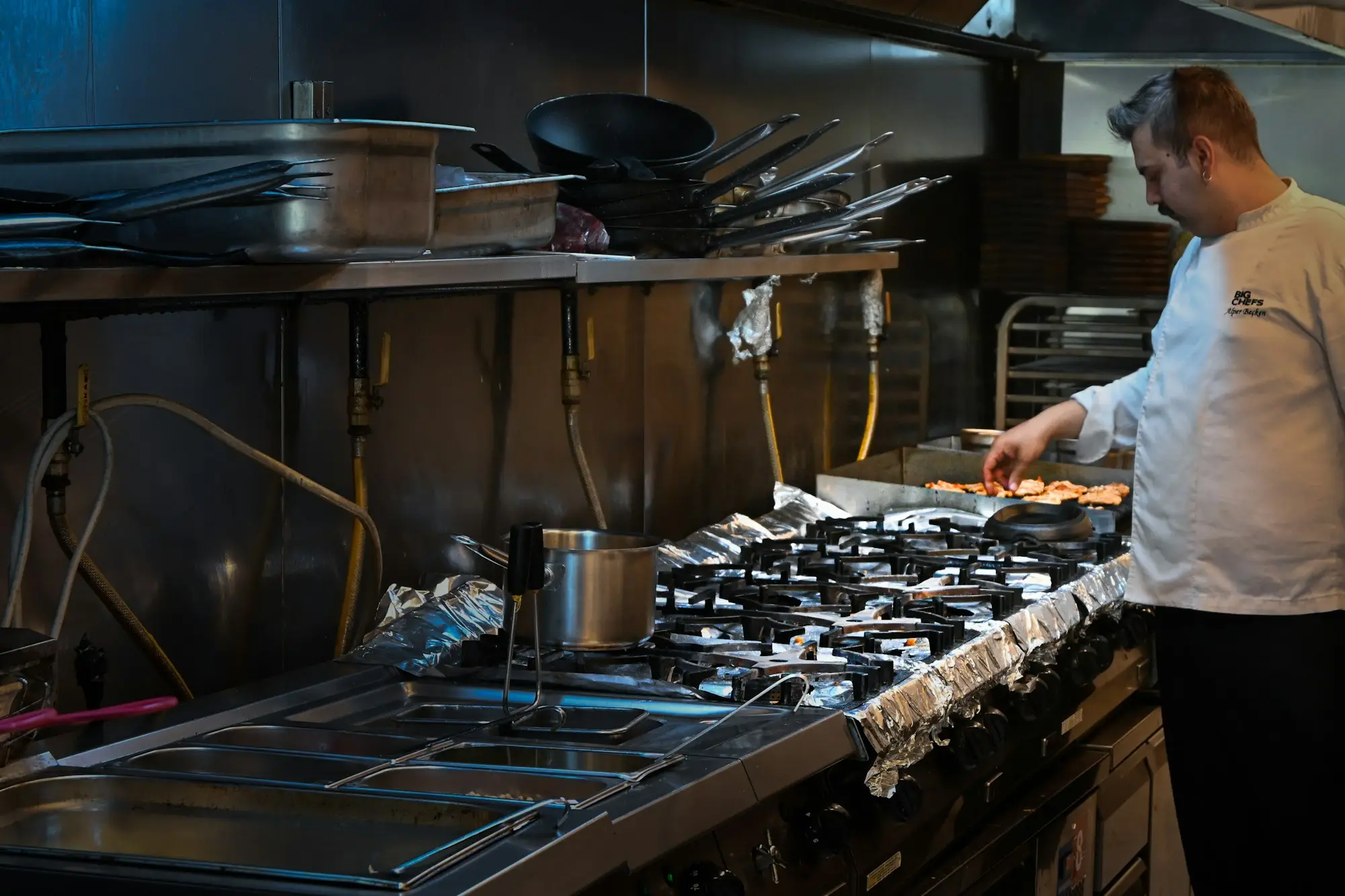 Chef cooking on an induction cooktop in a commercial kitchen, illustrating a gas to electric kitchen conversion