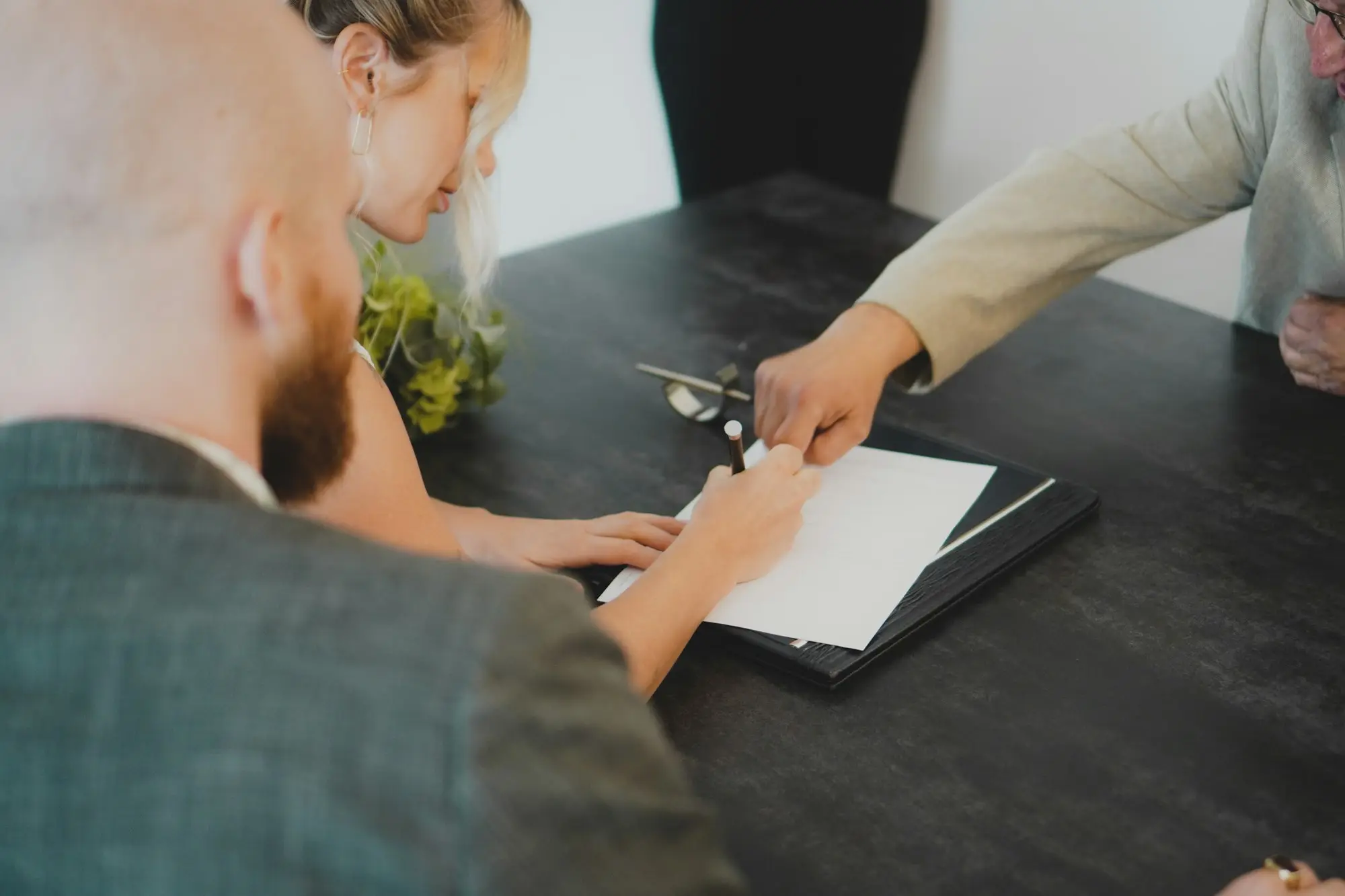Company directors signing home equity business loan documents at their dining table, deciding whose name the loan should be in