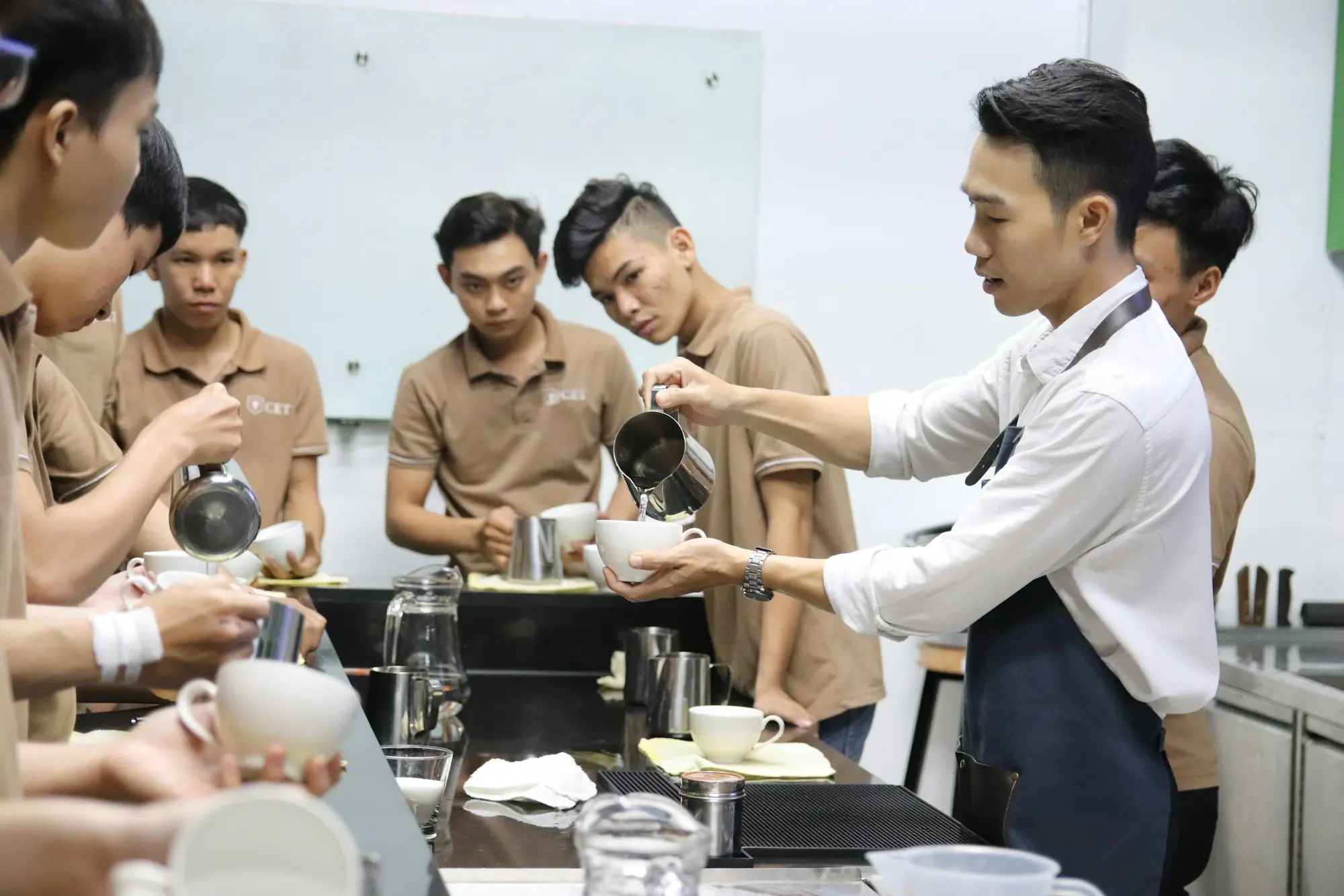 Café manager training new seasonal staff behind the counter, funded with a pre-season hiring loan before the summer rush