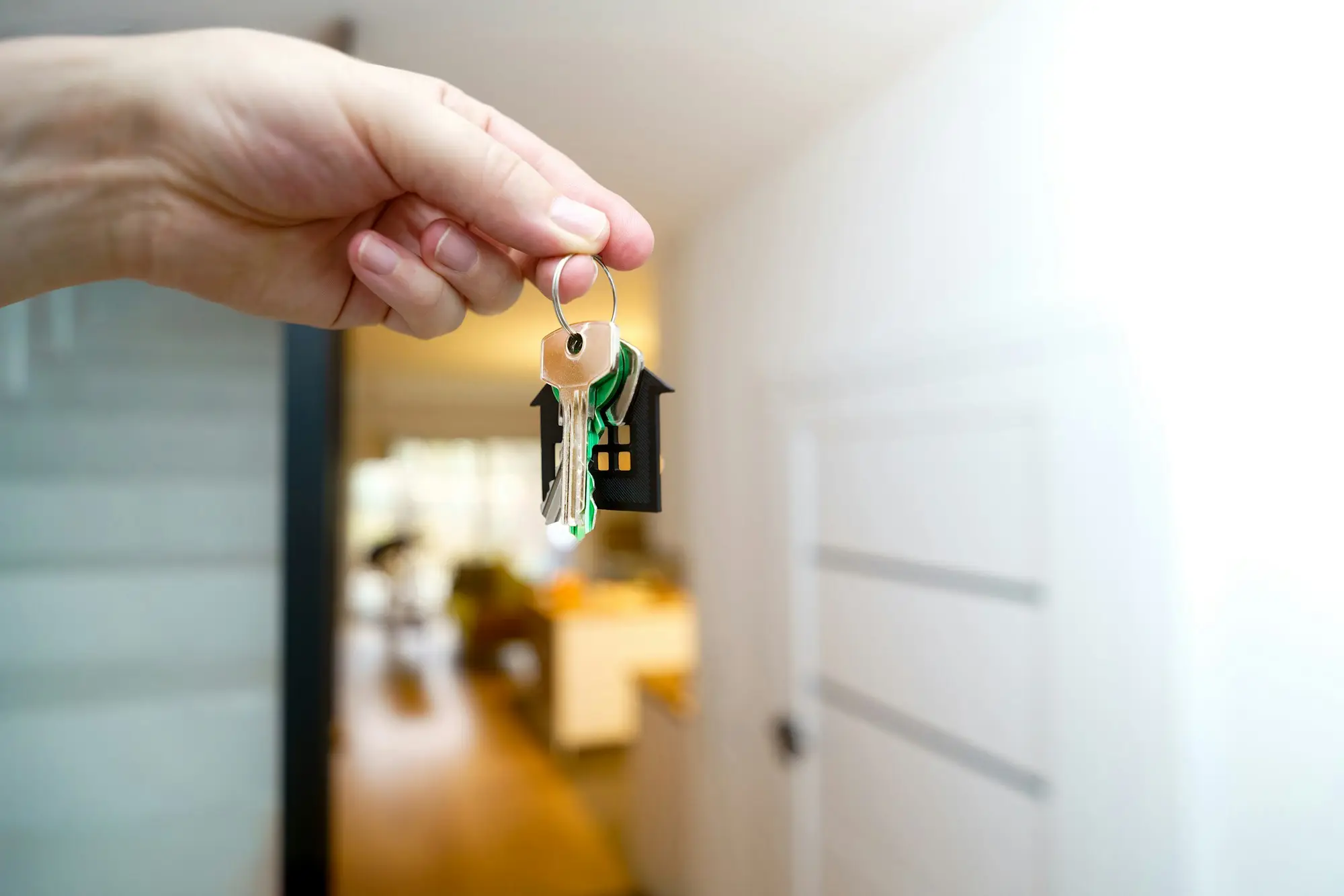 Hand holding house keys at a front door, property used as security for a private mortgage