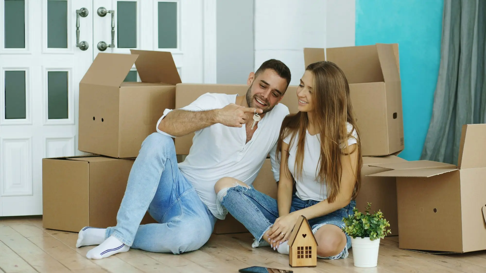 New tenants sitting among moving boxes holding the keys to their rental home, the kind of managed tenancy a rent roll is built on