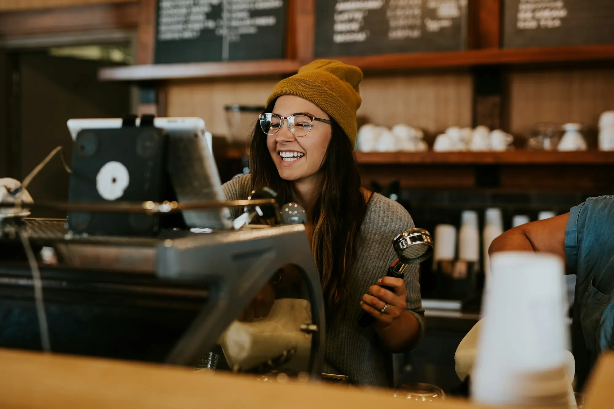 Barista smiling while making coffee in a busy coffee shop she runs