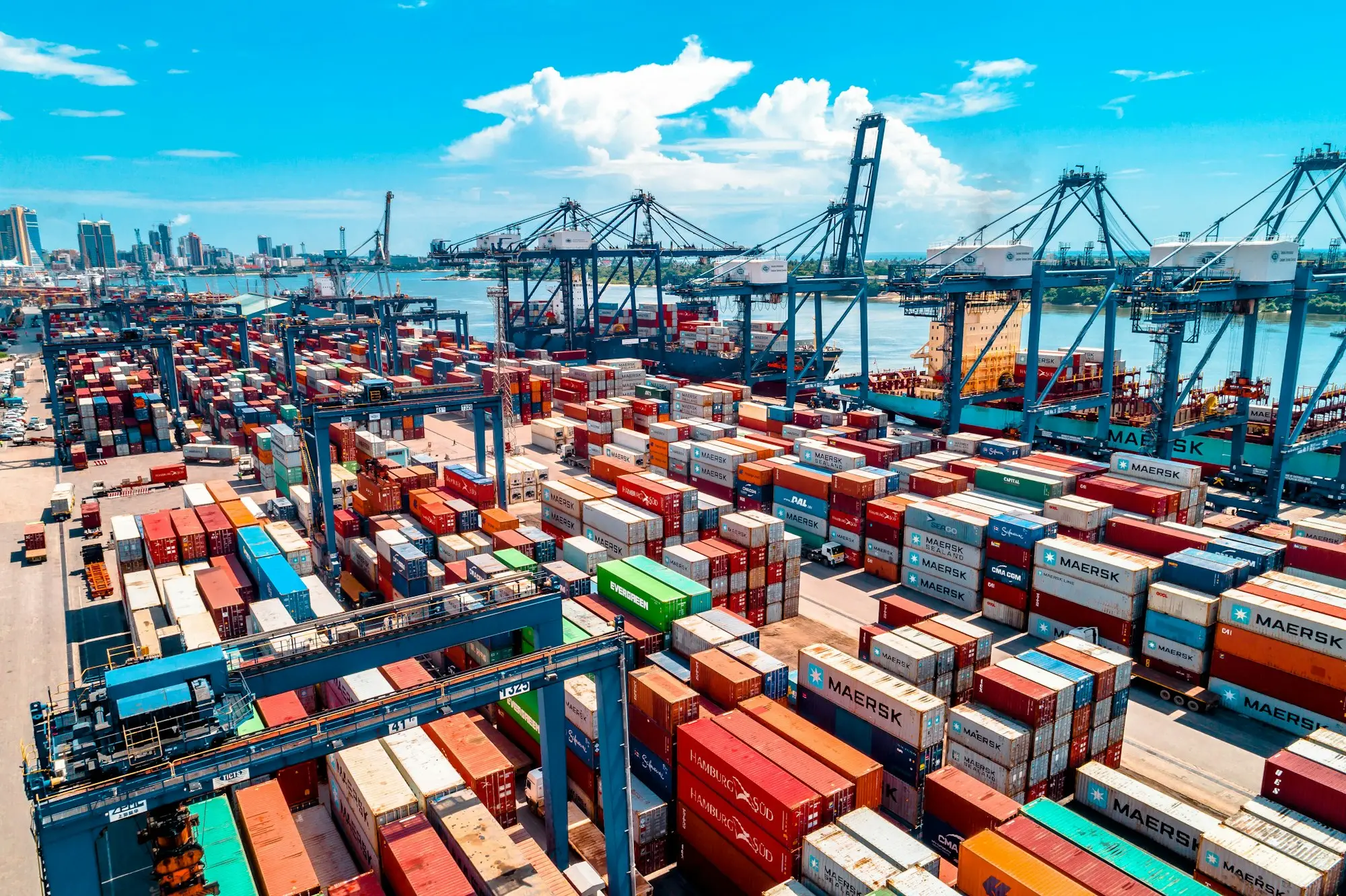 Stacked shipping containers at a busy port, goods moving on trade finance