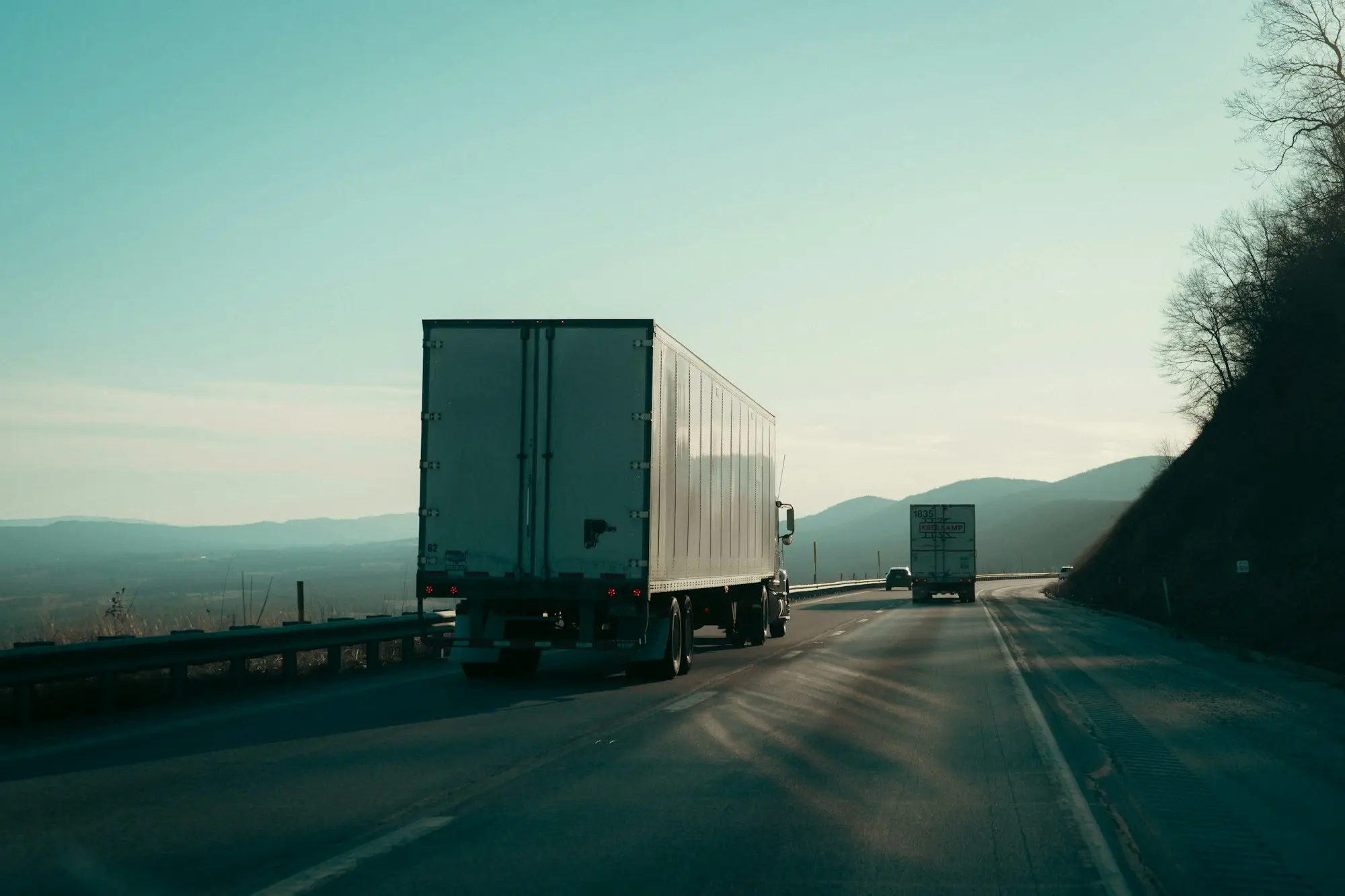 Two prime movers hauling trailers along an open highway, the kind of rig truck finance pays for
