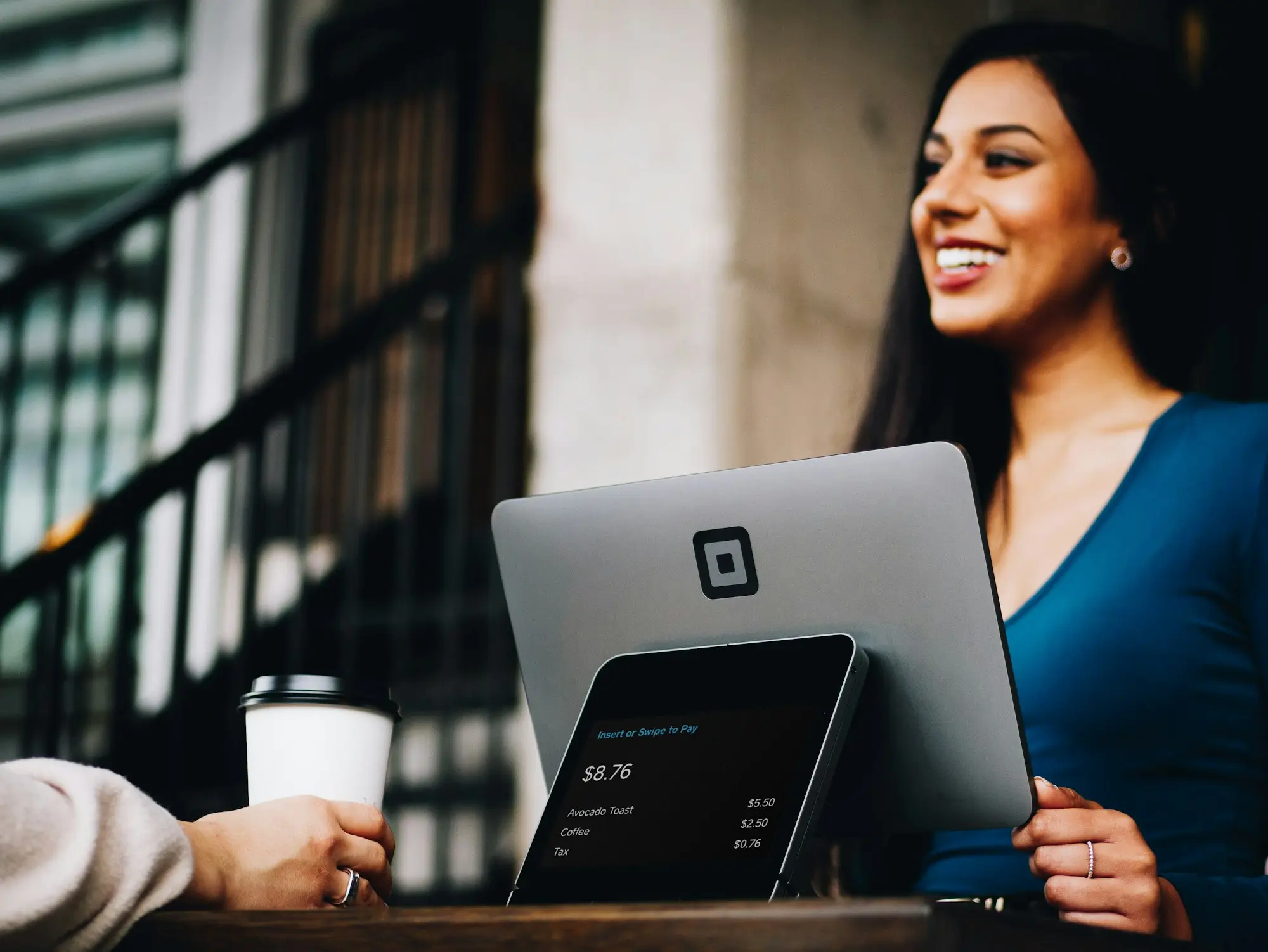 Smiling small business owner with a card payment terminal, trading income behind an unsecured business loan