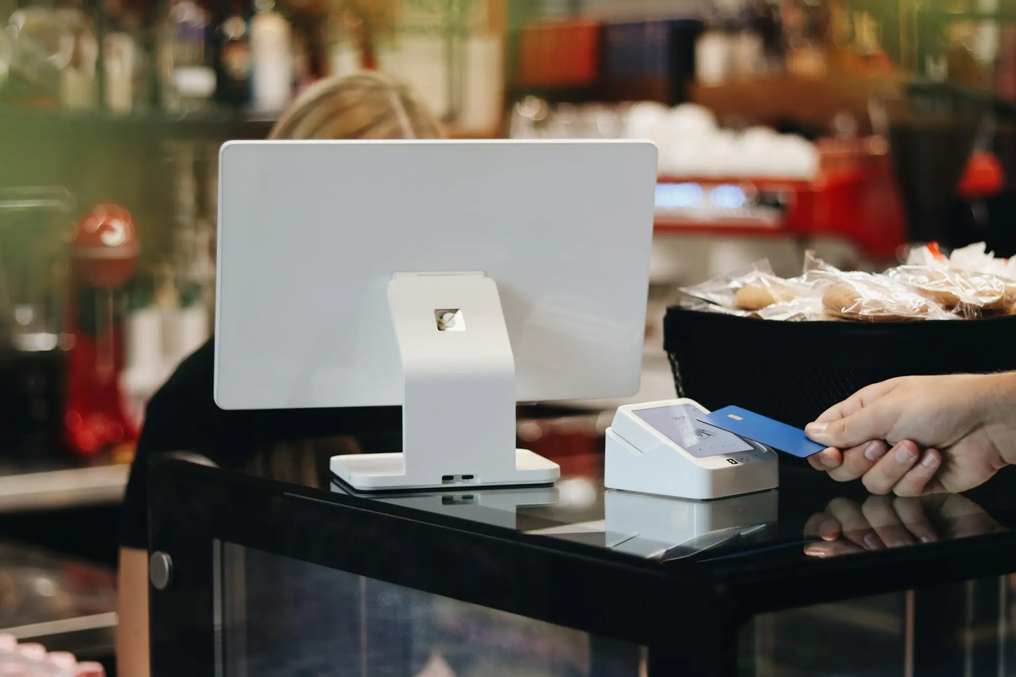 Several unused business and personal credit cards on a café counter beside a laptop, as the owner reviews credit limits before a loan application