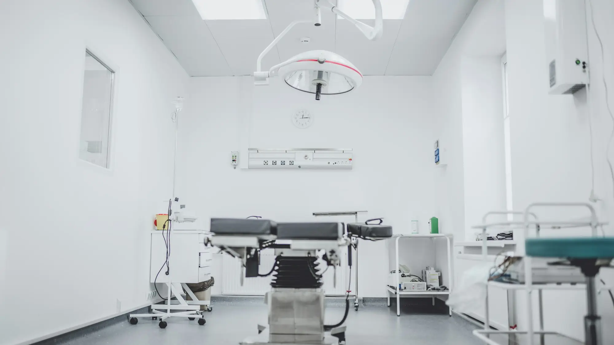 Bright clinic surgical suite with an overhead light, operating table and monitoring equipment, the kind of fit-out a veterinary practice finances