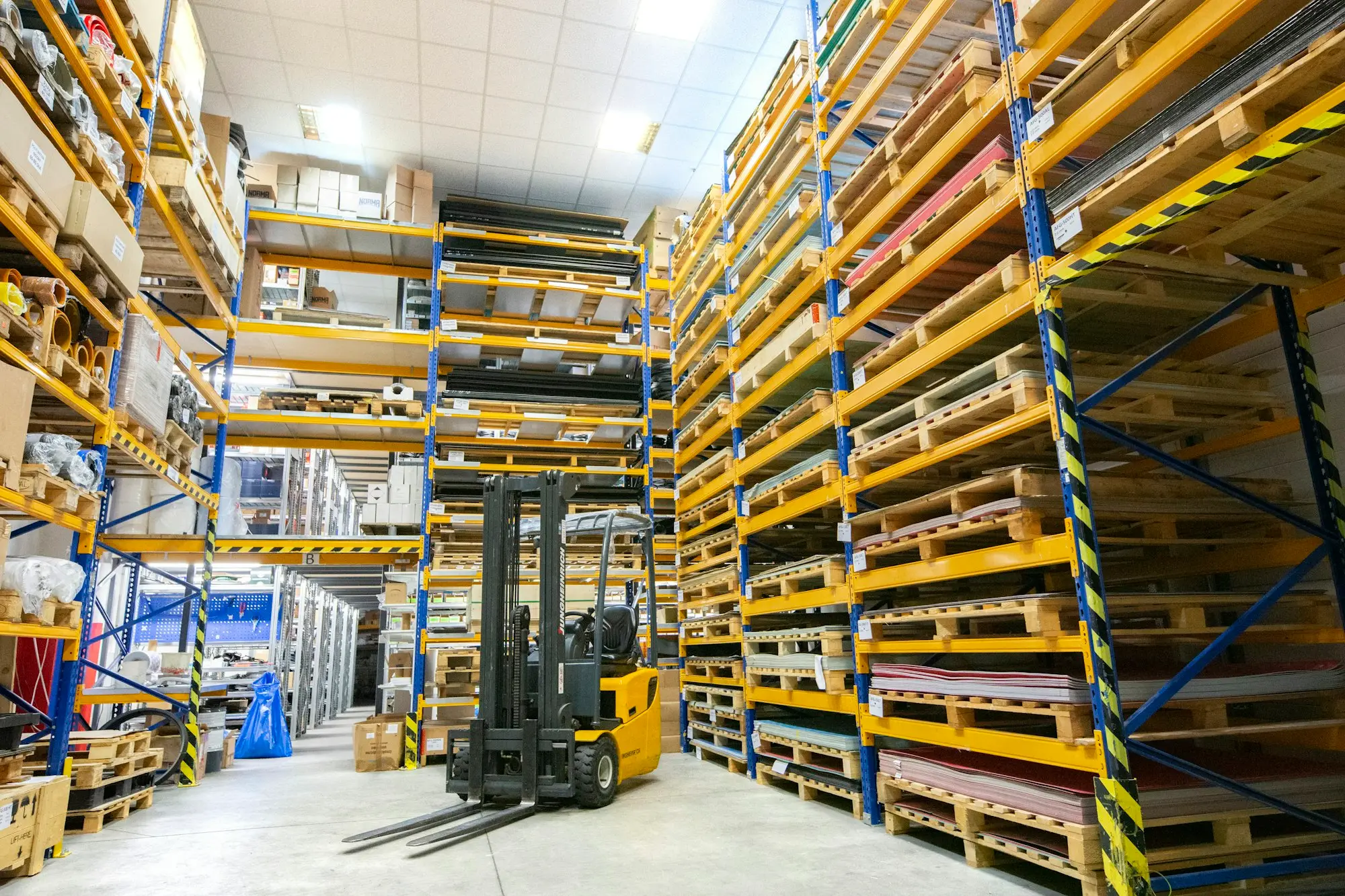 Forklift moving through a newly fitted warehouse aisle lined with pallet racking funded by warehouse fit-out finance